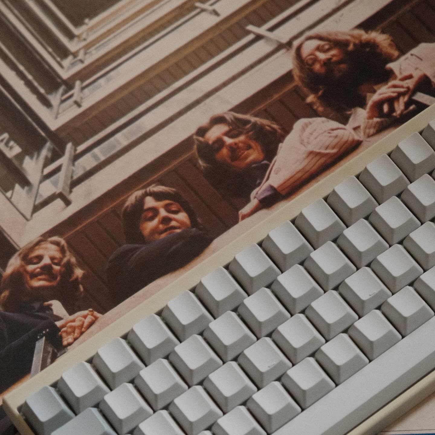 The Beatles posed above white computer keyboard in retro-style photograph